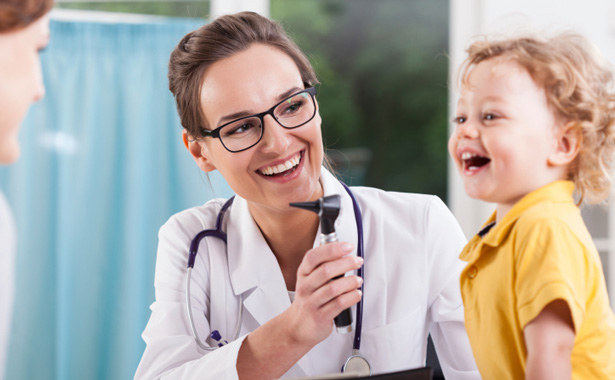 happy doctor looks at smiling child in yellow shirt