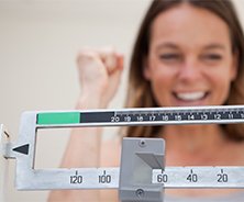 Patient smiling behind a weight scale