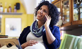 pregnant african-american woman talks on her cell phone at a coffee shop